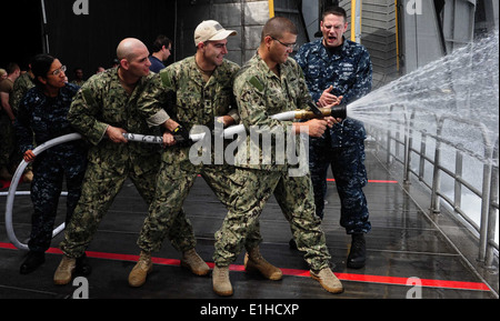 U.S. Navy Culinary Specialist 2nd Class Howard LeRoy, right, explains hose-handling techniques to Sailors during damage contro Stock Photo