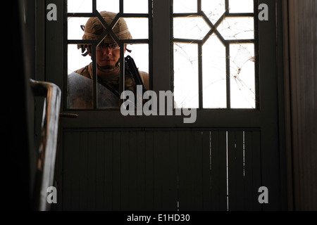 U.S. Army Sgt. Joseph Meachem looks through a door while providing security during a poetry workshop hosted by the Kandahar dir Stock Photo