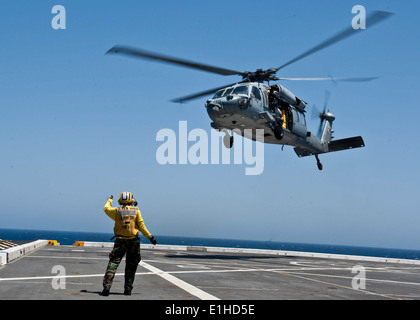 An MH-60S KnightHawk helicopter attached to Helicopter Sea Combat Squadron (HSC) 22 takes off from amphibious transport dock s Stock Photo