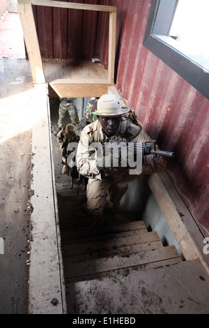 A Senegalese special operations forces member runs up a staircase to clear the second floor of a building during urban operatio Stock Photo