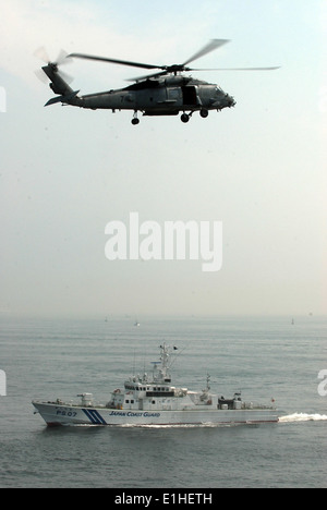 An U.S. Navy HH-60H Seahawk helicopter attached to Helicopter Anti-Submarine Squadron (HS) 14 flies above a Japanese Coast Guar Stock Photo