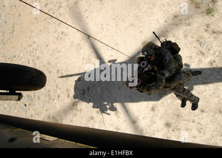 A pararescue jumper and a combat rescue officer from the 83rd Expeditionary Rescue Squadron are hoisted into a U.S. Air Force H Stock Photo