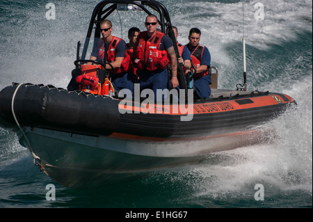 U.S. Coast Guardsmen assigned to medium endurance cutter USCGC Escanaba (WMEC 907) navigate alongside the cutter in a rubber re Stock Photo