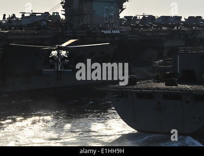 A U.S. Navy MH-60S Knighthawk helicopter prepares to pick up cargo from the fast combat support ship USNS Supply (T-AOE 6) duri Stock Photo