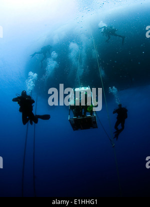 Navy divers, assigned to Mobile Diving and Salvage Unit 2, Company 4, and the Joint POW/MIA Accounting Command, descend on a st Stock Photo