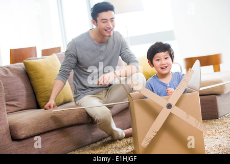 Happy father and son playing cardboard airplane Stock Photo