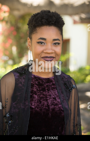 Outdoor portrait of a Black young woman in a purple velvet gown Stock Photo