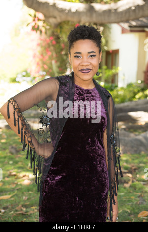 Outdoor portrait of a Black young woman in a purple velvet gown Stock Photo