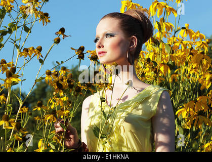 Summertime. Young Female in Meadow among Blooming Yellow Flowers