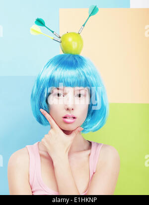 Creativity. Woman with Painted Blue Hairs and Apple on her Head Stock Photo