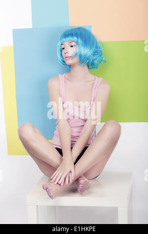 Patchwork. Funky Girl in Azure Wig Sitting in Studio on White Chair Stock Photo