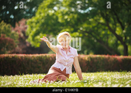 Enjoyment. Positive Emotions. Outgoing Old Woman Resting on Grass Stock Photo