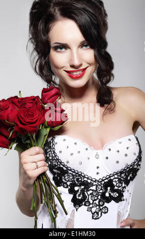 Fragrance. Beautiful Young Woman Holding Bouquet of Red Roses. Valentine's Day Stock Photo