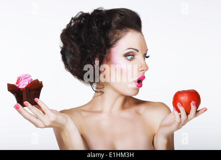 Surprised Funny Woman Decides between Apple and Cake Stock Photo