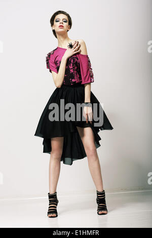 Tendency. Glamorous Fashion Model in Modern Clothes posing in Studio Stock Photo