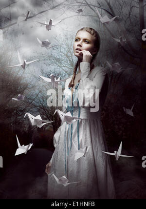 Night. Woman in  Mysterious Forest launching handmade paper Cranes. Origami Stock Photo