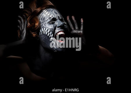 Art photo of a stressed ethnic woman with black painted mask on face and tattoo Stock Photo