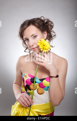 Lovely young female in bright multicolor dress posing with flowers - series of photos Stock Photo