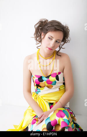 Fine portrait of young lovely sad girl in colorful bright dress. Studio shot Stock Photo