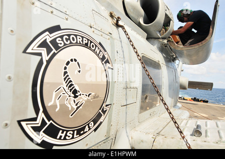 US Navy Electrician's Mate 2nd Class solders the wiring of a vent motor ...