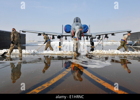 U.S. Airmen assigned to the 455th Expeditionary Aircraft Maintenance Squadron clear snow around an A-10 Thunderbolt II at Bagra Stock Photo