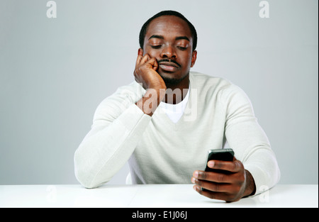 Pensive african man using smartphone on gray background Stock Photo
