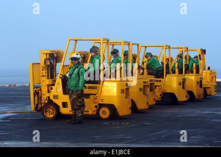 Sailors wait in their forklifts for incoming cargo on the flight deck of the aircraft carrier USS John C. Stennis (CVN 74) duri Stock Photo