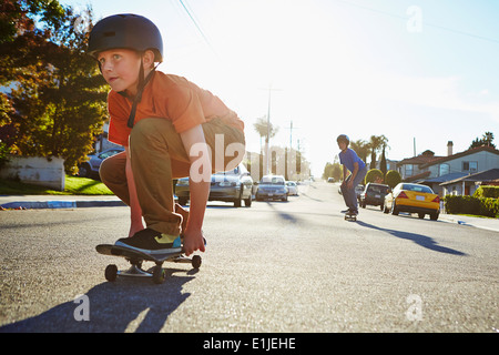 Two boys skateboarding on suburban road Stock Photo