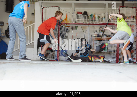 Boys playing hockey in garage Stock Photo