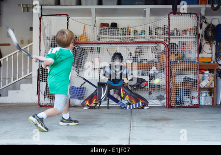 Boys playing hockey in garage Stock Photo