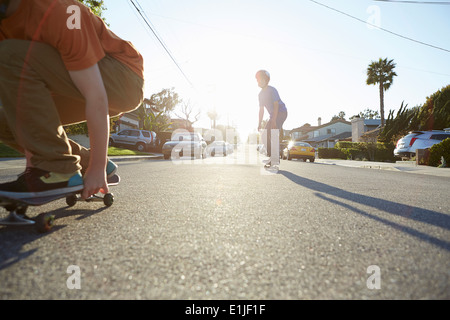 Boys skateboarding on road Stock Photo