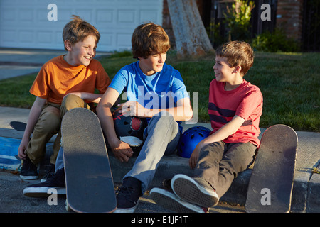 Boys sitting on pavement with skateboards Stock Photo