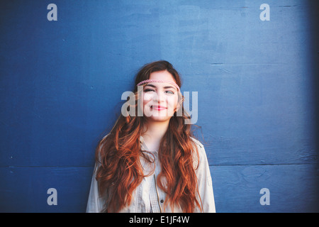Portrait of young woman leaning against blue wall
