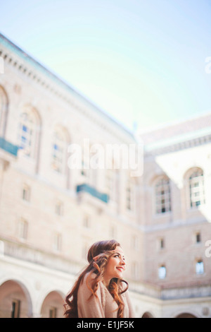 Young woman gazing upward in historic courtyard Stock Photo