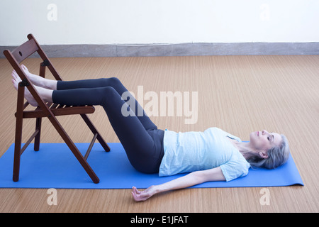 Mature woman resting legs on chair Stock Photo