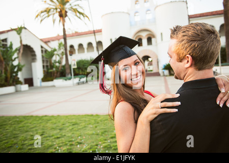Female graduate hugging man Stock Photo