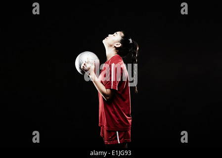 Young woman holding football, looking up Stock Photo