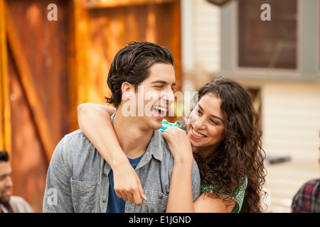 Couple in garden, with arm around, friends in background Stock Photo