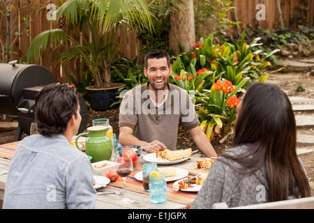 Friends sitting around table sharing barbecue food Stock Photo
