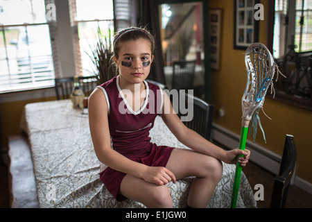 Girl wearing lacrosse uniform, sitting on dining table Stock Photo