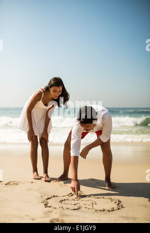 Couple drawing in sand on Arpoador beach, Rio De Janeiro, Brazil Stock Photo