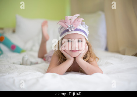 Portrait of young girl in princess headdress on bed Stock Photo