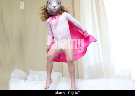 Young girl dressed up as a rabbit princess dancing on bed Stock Photo