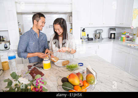 Mid adult couple preparing sandwich in kitchen Stock Photo