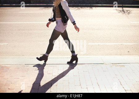 Young woman with camera walking down street Stock Photo