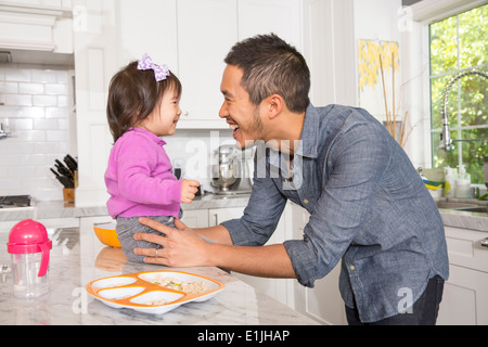 Mid adult man with toddler daughter on kitchen counter Stock Photo