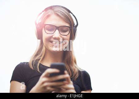 Young woman wearing headphones using smartphone Stock Photo