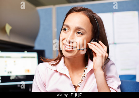 Young female office worker using headset in office Stock Photo