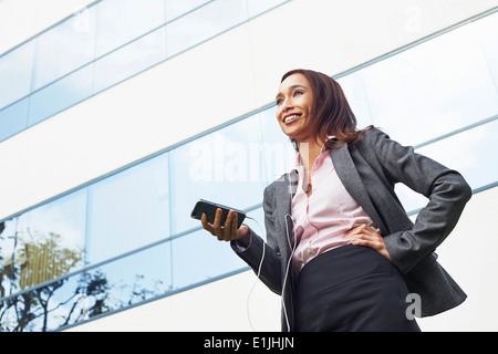 Young female businesswoman using smartphone outside office Stock Photo