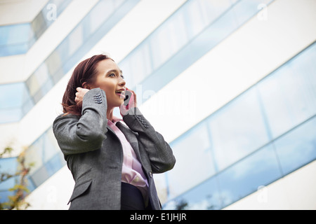 Young female businesswoman talking on smartphone outside office Stock Photo